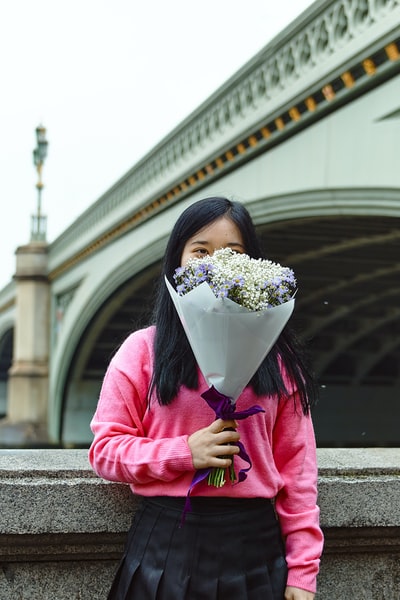 穿着粉色长袖衬衫的女人手里拿着一束花
